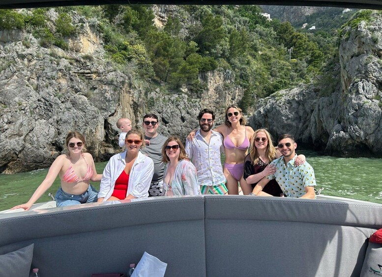 Un gruppo di persone su una barca, con scogliere rocciose e vegetazione sullo sfondo. 4