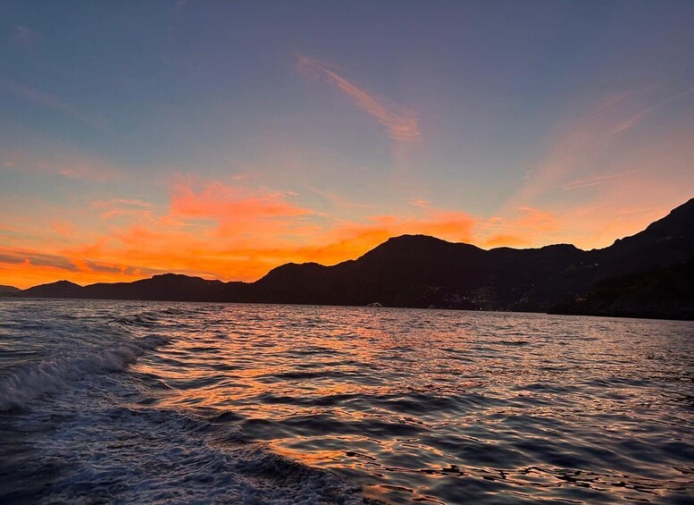 Un tramonto sul mare calmo con montagne sullo sfondo. 2