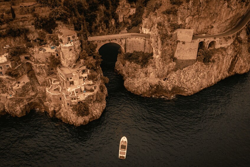 Una barca su un fiume, un ponte e una struttura simile a un castello su una scogliera. 3