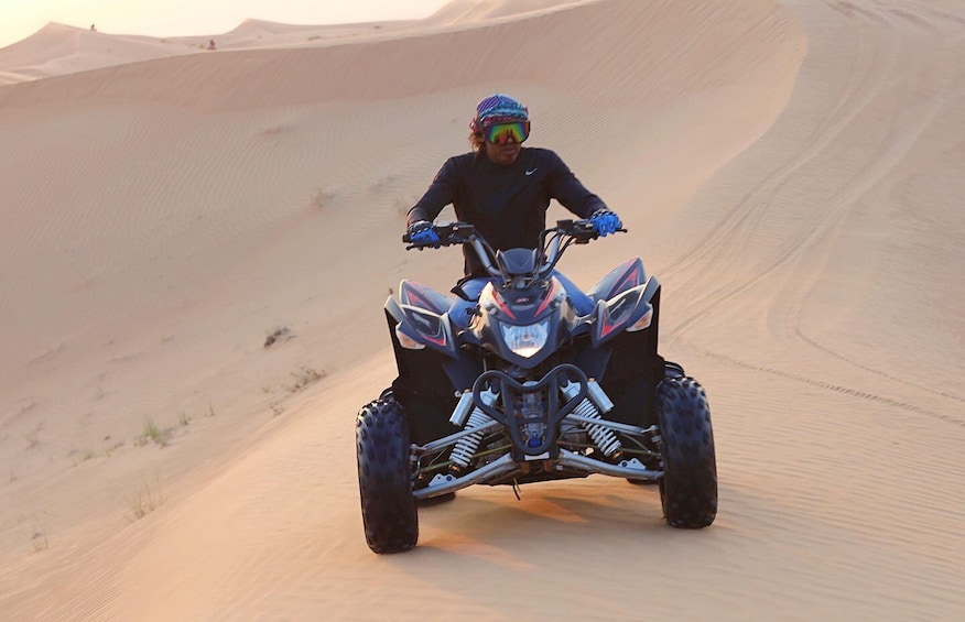 A person riding a quad bike on a sandy dune. 4