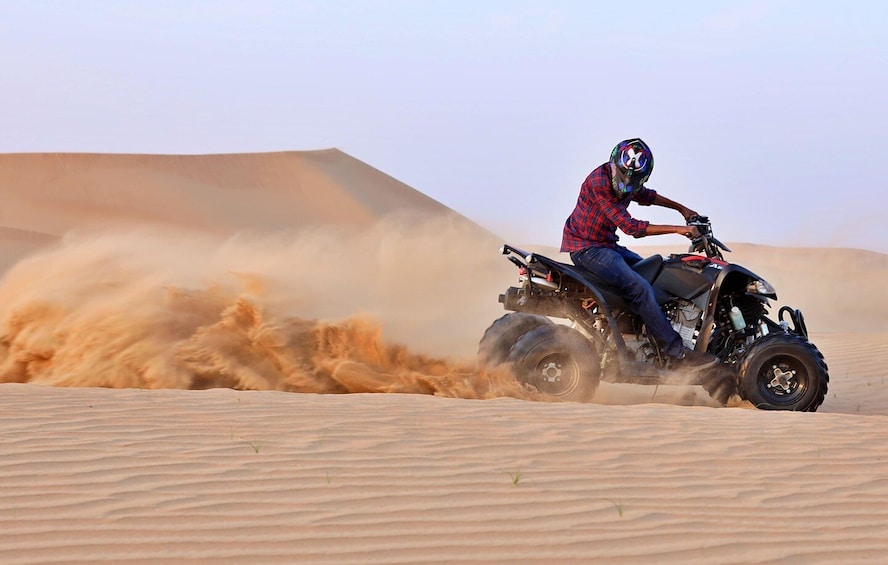 A person riding an ATV in a desert with sand dunes. 2