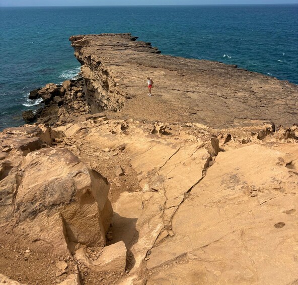 A rocky coastline with a person standing on the edge. 3