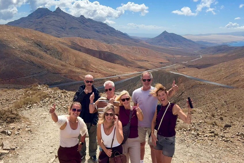 A group of people on a mountain trail with a road in the valley. 1