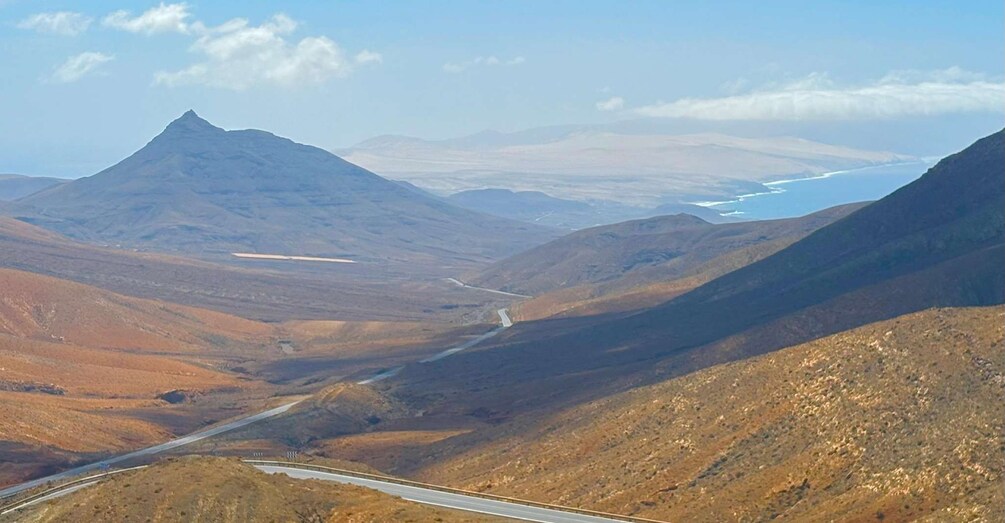 A mountainous landscape with a winding road and a distant body of water. 4