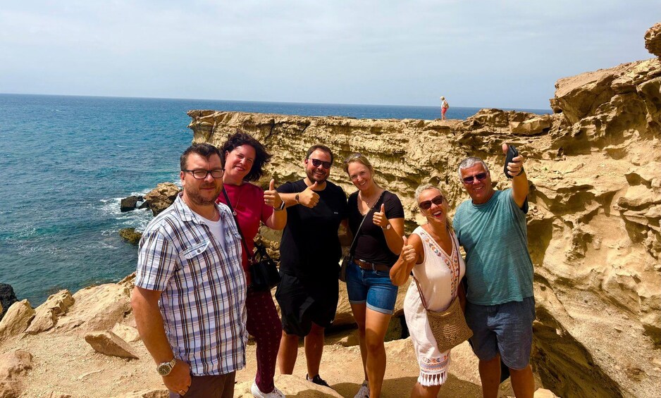 A group of people on a rocky cliff by the sea. 2