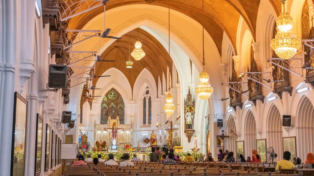 An interior of a cathedral with high vaulted ceilings, ornate chandeliers, and a central altar. 2