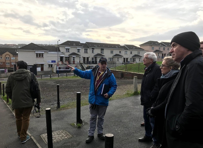 A group of people on a sidewalk with houses in the background. 2