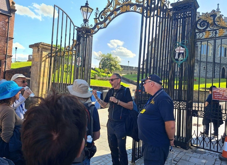 A group of people standing at a historic gate with ornate ironwork and a sign indicating Saint Columba's Cathedral. 4