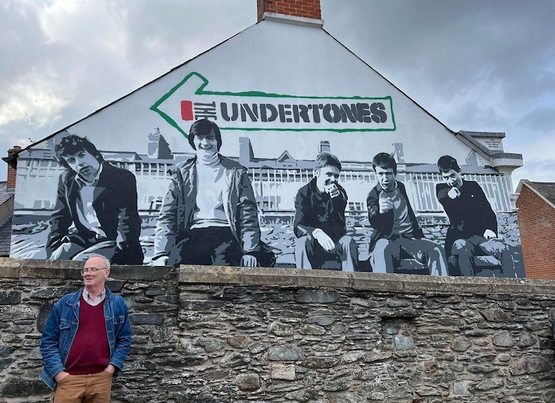 A mural of five men on a wall with the word "UNDERTONES" and a green arrow pointing left. 1
