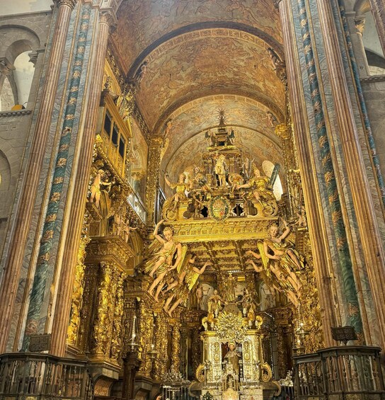 An ornate religious interior with golden statues and intricate ceiling artwork. 5