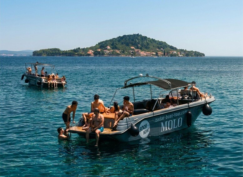 A boat tour with people on a lake, a small island in the background, and clear skies. 3