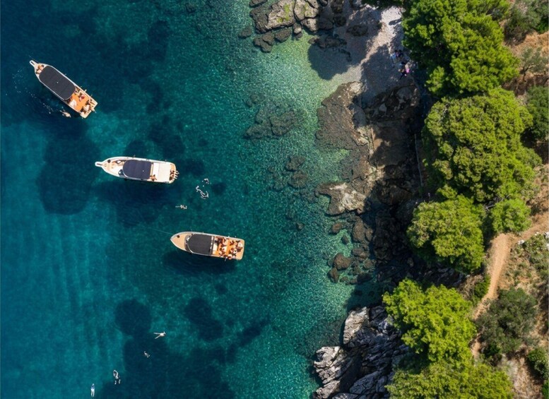 Three boats anchored near a rocky shoreline with clear turquoise water. 5