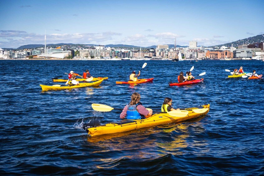 Persone che fanno kayak su acque calme, con uno skyline urbano sullo sfondo. 4