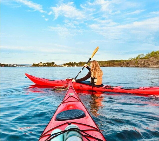 Una persona fa kayak su un lago calmo, con un kayak rosso, un altro kayak in primo piano e un cielo sereno. 5