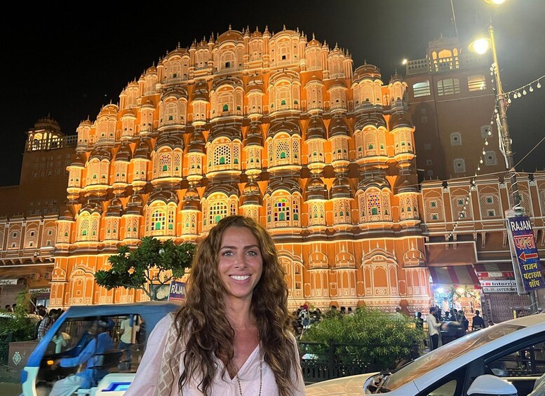 A woman standing in front of a brightly lit, ornate building with multiple domes and intricate designs. 3