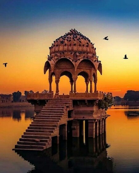 Un padiglione storico con elaborate decorazioni, situato su un corso d'acqua al tramonto. 4