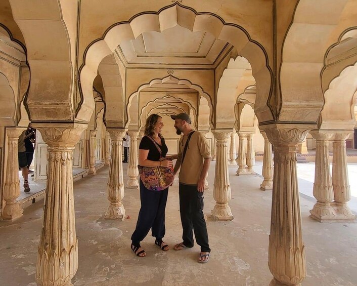 A man and a woman standing in an architectural space with arches and columns. 2