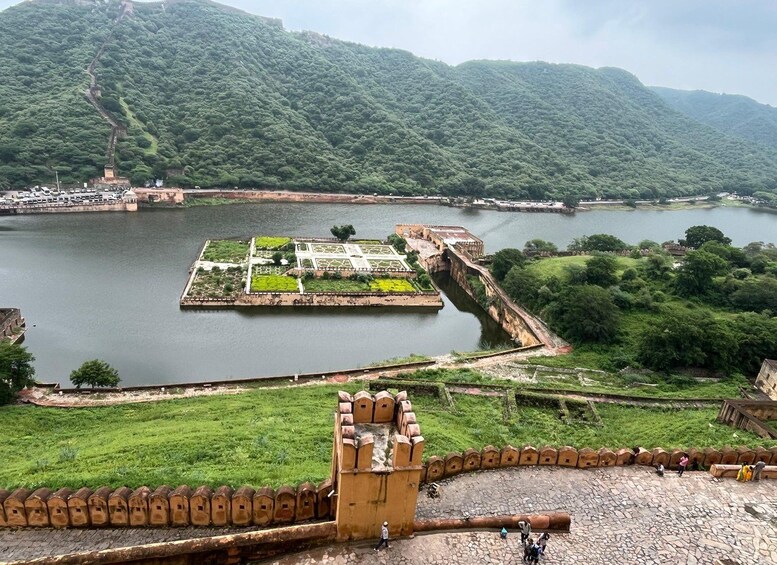 A historic fort with a moat, lush green hills in the background, and a small island with a garden. 4