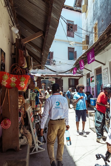 A street market with people walking and shops selling bags and textiles. 3