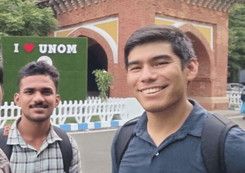 Two individuals in front of a building with a sign that reads 'I ♥ UNOM.' 3