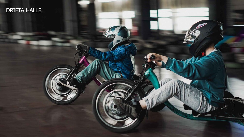 Two people on a tandem bike in an indoor setting. 1