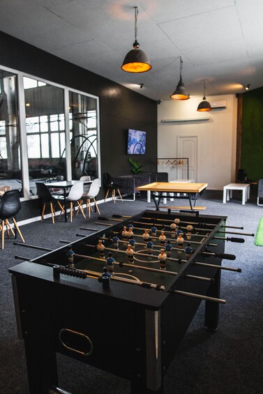 A foosball table in a modern office setting with chairs, a table, and pendant lights. 4
