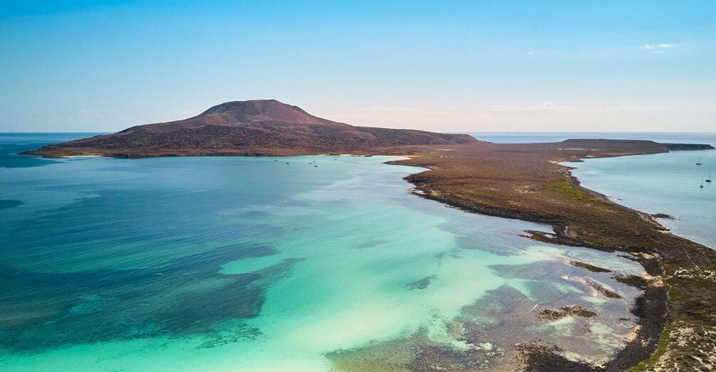 A coastal landscape with a prominent hill and clear turquoise waters. 5
