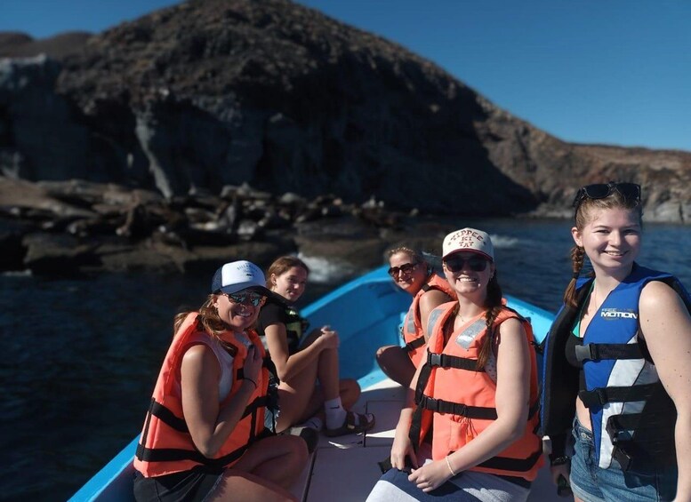 A group of people on a boat with rocky cliffs in the background. 3