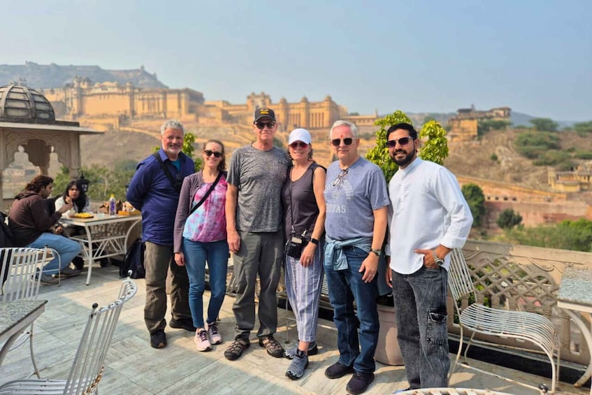 A group of people standing on a terrace with a view of ancient ruins in the background. 5