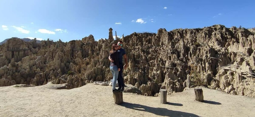 A person standing on a sandy beach with a rocky cliff in the background. 2