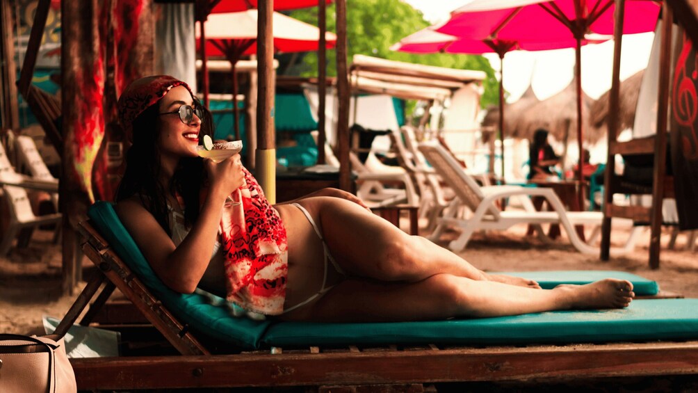 A person relaxing on a sun lounger with a beach umbrella in the background. 5