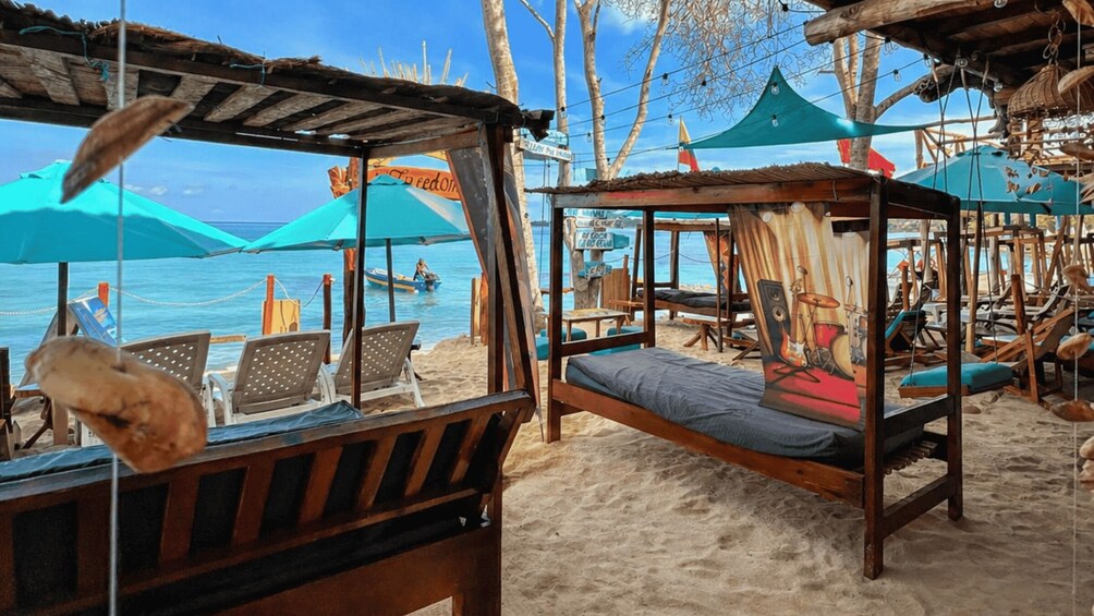 A beach with wooden beds and umbrellas, a clear sky, and the sea in the background. 4