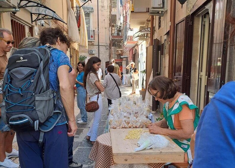 People standing and interacting near a table with food items. 1