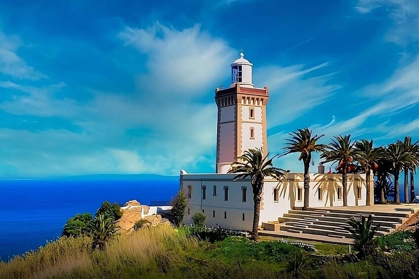 A lighthouse with a white tower and red roof, surrounded by palm trees and a building with steps leading up to it. 3