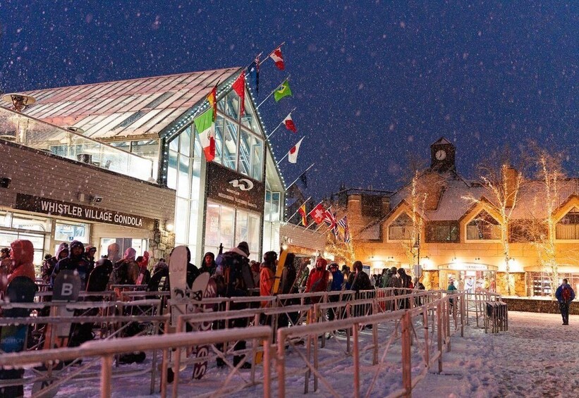 A snowy outdoor market with a building labeled "Whistler Village Gondola" and a clock tower. 1