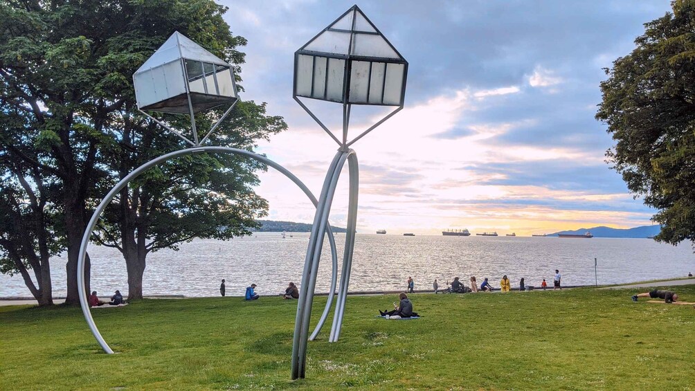 A park with a unique sculpture, a lake, and boats in the distance. 2