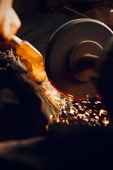 A person sharpening a knife with a grinding wheel, producing sparks. 2