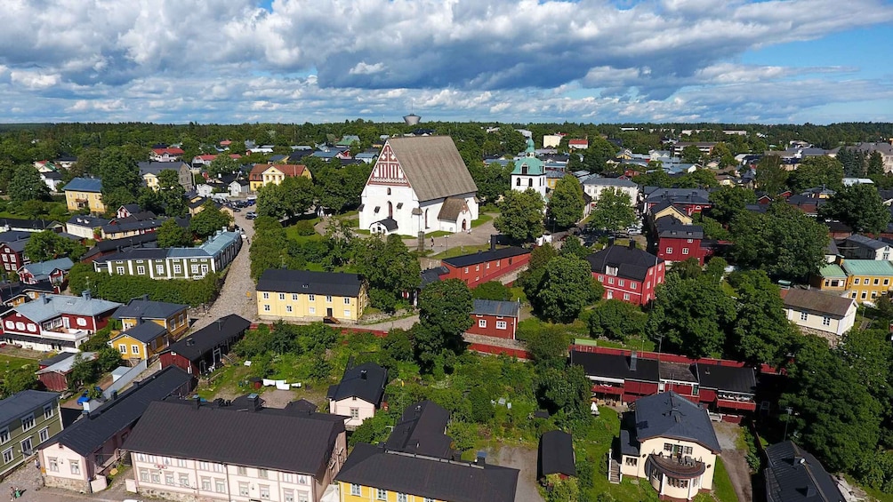 Kaupungissa on huomattava kirkko, värikkäitä taloja ja taustalla tiheä metsä. 1