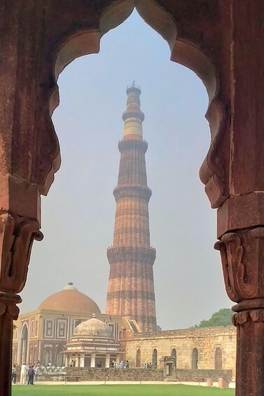 A tall minaret with a dome, viewed through an archway. 1
