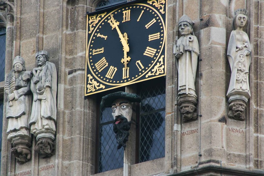 Eine Uhr mit römischen Ziffern und eine Statue eines Mannes mit Bart. 5