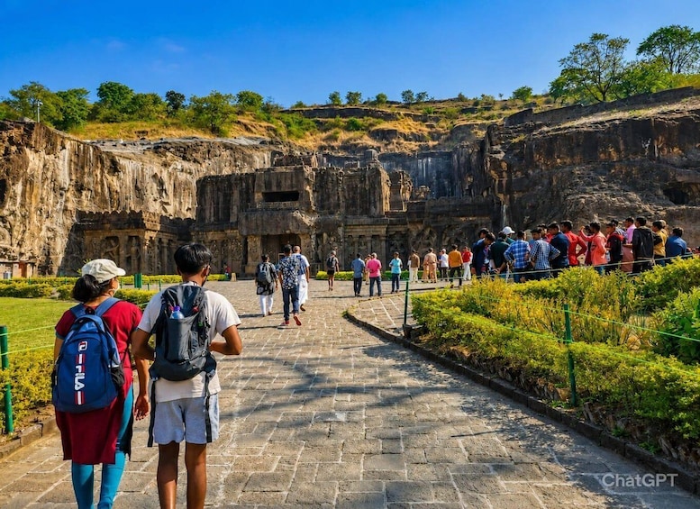 A group of people walking towards a large ancient rock structure with detailed carvings. 4