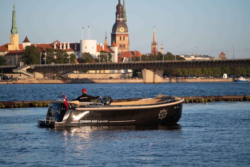 A boat named 'Corsiva 650 tender' on a river with a cityscape in the background. 5
