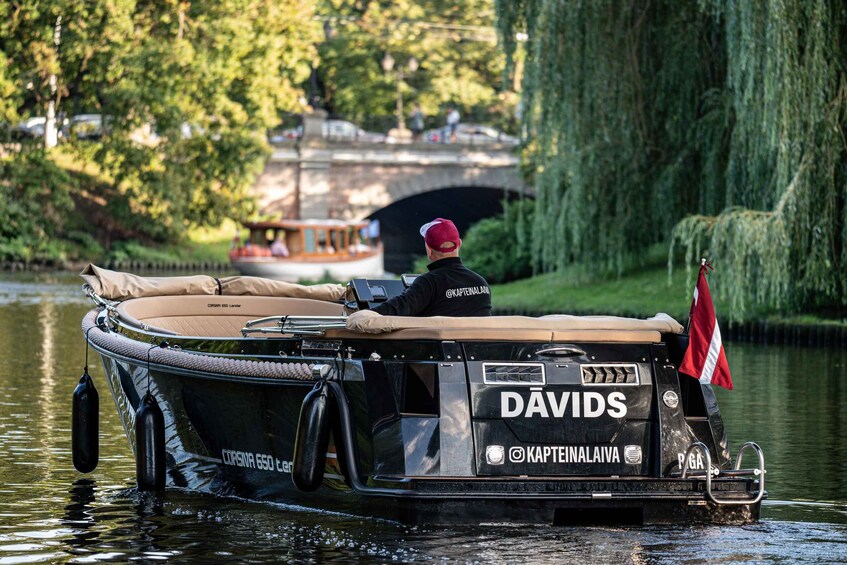 A boat named DAVIDS on a river, with a person wearing a red cap and a black jacket. 3