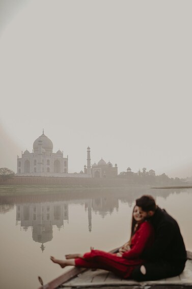 Une personne assise sur un bateau devant le Taj Mahal, son reflet se devinant dans l’eau. 2
