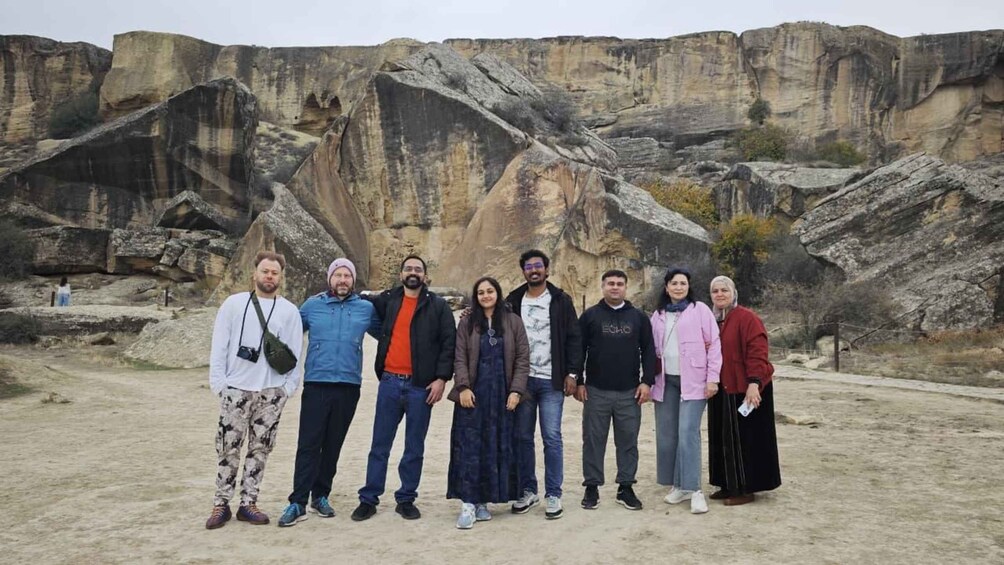 A group of people standing in front of a rocky landscape with layered sedimentary cliffs. 2