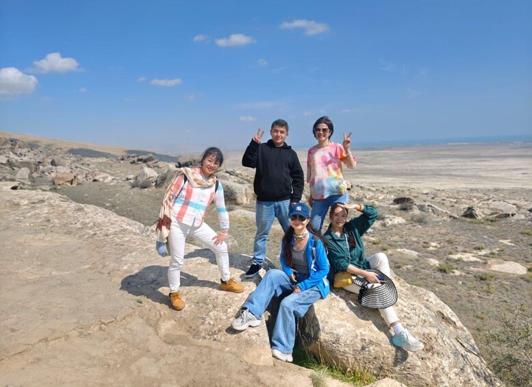 A group of people posing on a rocky outcrop with a desert landscape in the background. 4
