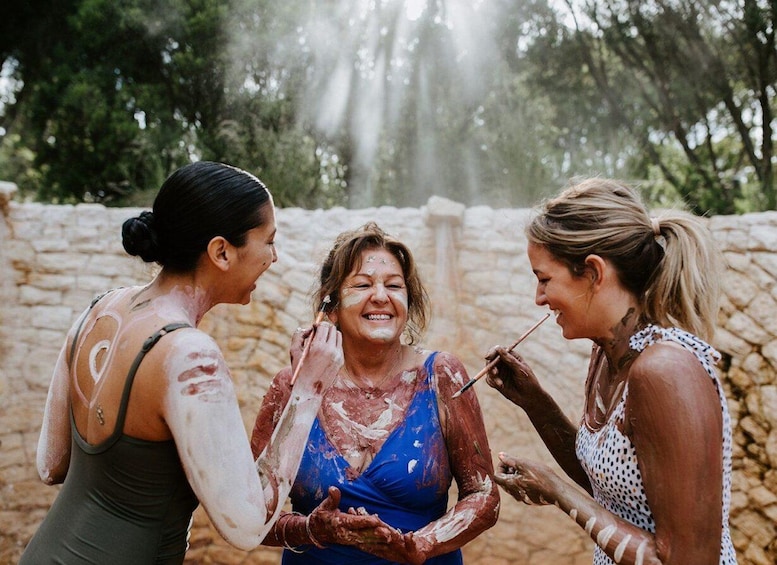 Three people covered in paint, standing in front of a stone wall. 1