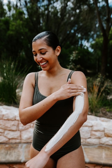 A person applying sunscreen on their arm. 2