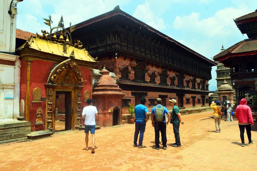 Un groupe de personnes se tient devant un bâtiment traditionnel à la façade en briques rouges et aux décorations élaborées. 5