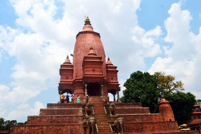 Un grand stupa en briques rouges, à plusieurs niveaux et surmonté d’un dôme central, entouré de statues de lions en pierre à sa base. 3